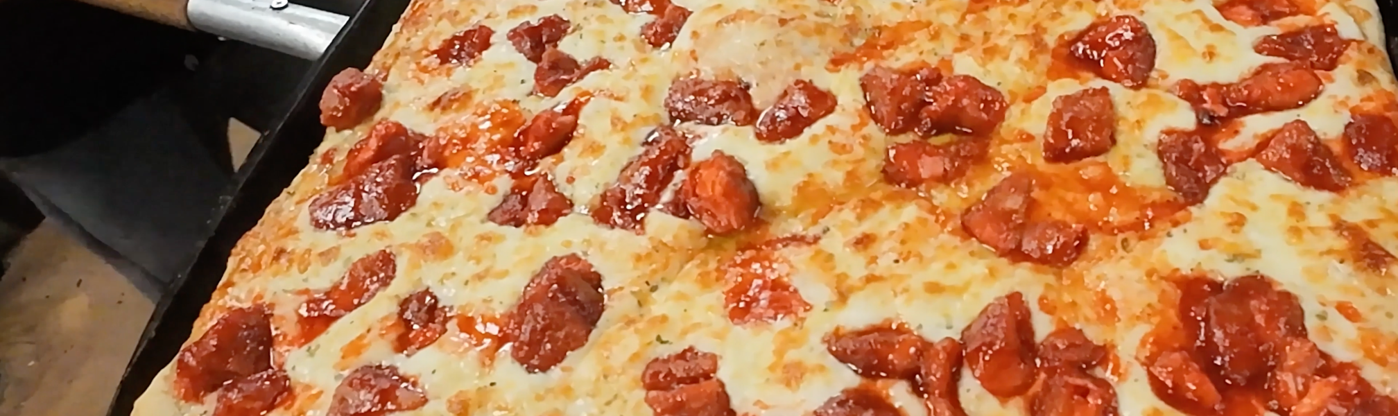 A zoomed in image of a bacon and cheese pizza.